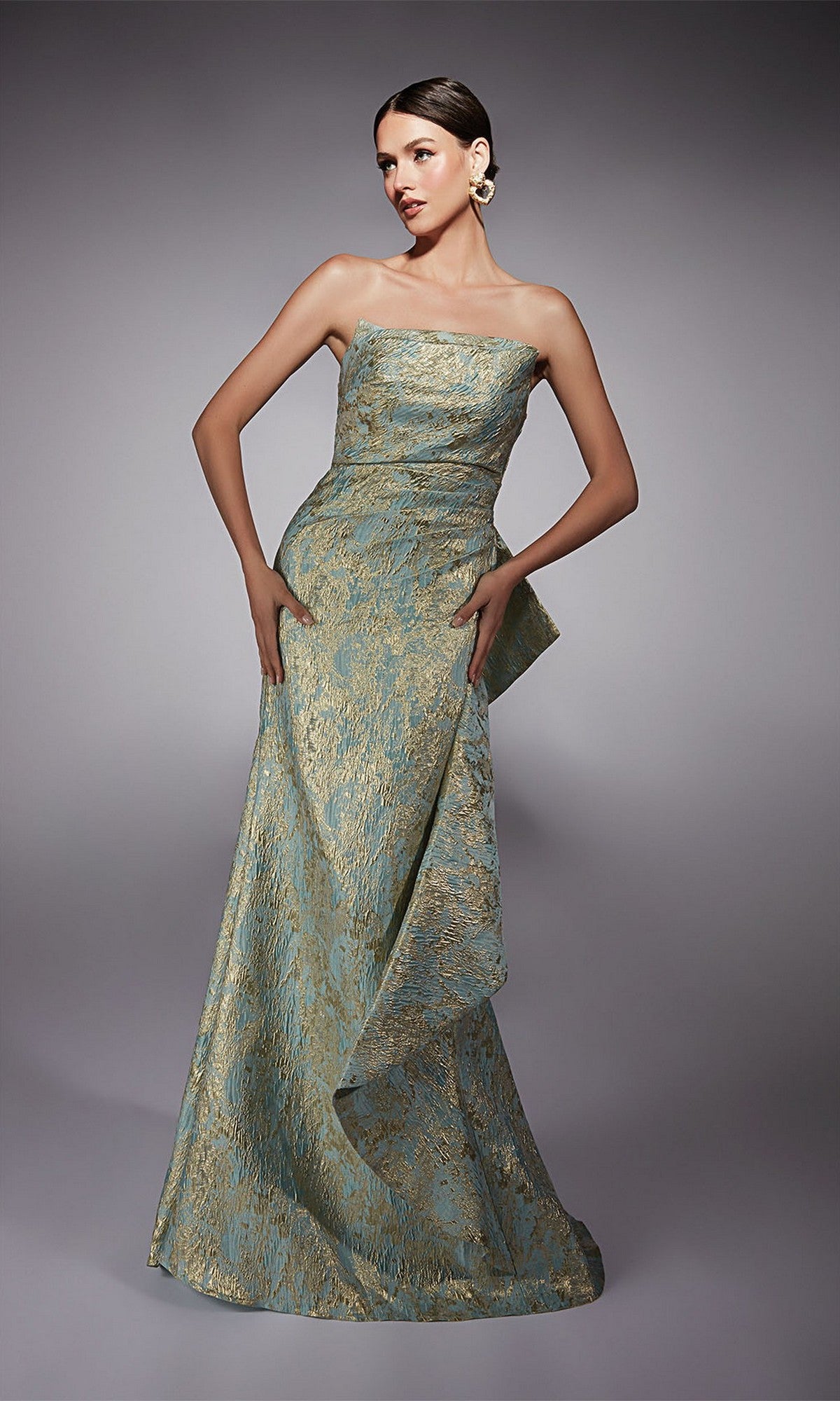 A woman poses in the Alyce 27750 long formal dress, a strapless mother-of-the-bride gown in pale blue and gold metallic jacquard brocade with a structured waist overlay and an elegant floor-length mermaid skirt.